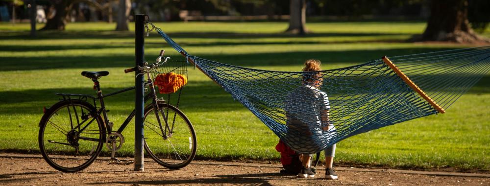 Student sitting in a hammock with a bicycle parked nearby